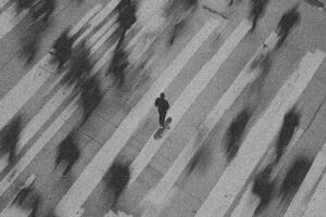a person standing in a middle of a busy streets as throngs of pedestrians move around them
